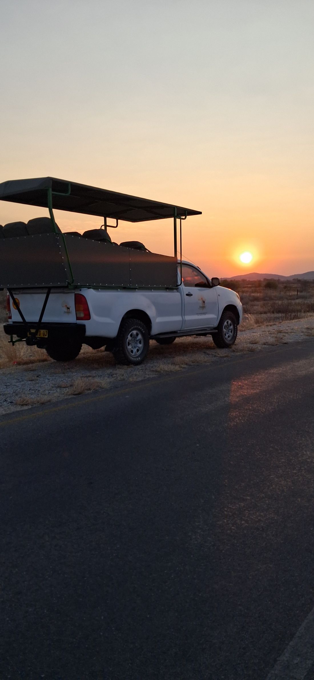 Oosino safari vehicle parked on the road at sunset